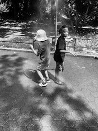 two boys playing in the park in black and white